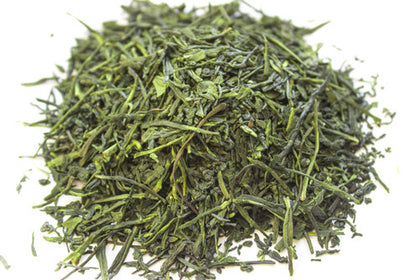Tas de feuilles de thé vert sencha séchées sur fond blanc