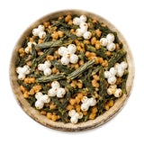 Genmaicha au riz soufflé de Fujinomiya : feuilles de thé vert et grains de riz soufflé dans une assiette en grès beige