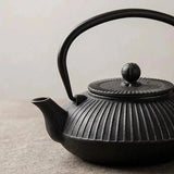 Gros plan d'une théière en fonte noire Tetsubin de 800 ml, design strié, anse haute et couvercle sur fond neutre.