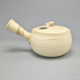 Théière Kyusu blanche et beige à motif tourbillon, vue de côté avec l'anse latérale à gauche