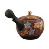 Théière Kyusu Kutani rouge à motif de raisins et feuilles dorées, vue de profil avec le bec à gauche, sur fond blanc