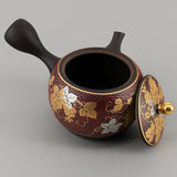 Théière Kyusu Kutani rouge à motif de raisins, vue de trois quarts avec le bec à droite et le bouton doré