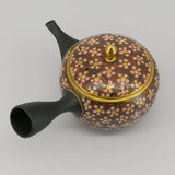 Théière Kyusu Kutani à fleurs de cerisier, vue de trois quarts avec le bouton doré et la grande anse noire