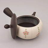 Théière Kyusu noire et blanche, couvercle posé à côté et intérieur ouvert, fleurs roses et vertes peintes